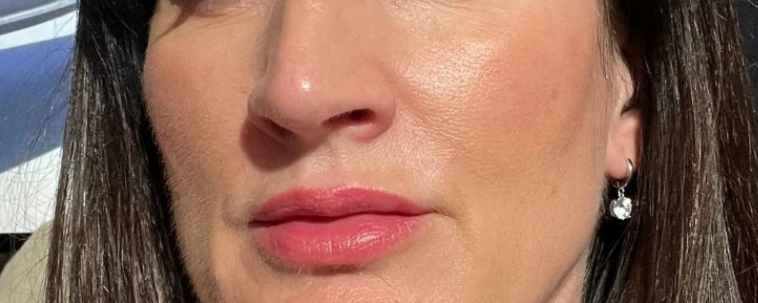 Close-up of a woman’s face showcasing glowing, radiant skin. The image highlights the smooth texture of her skin with a natural glow and soft makeup, including subtle pink lips. The woman has long, dark hair and is wearing a pair of hoop earrings. The glowing skin effect emphasises the skincare benefits of Face Junkie products, promoting healthy, luminous skin.