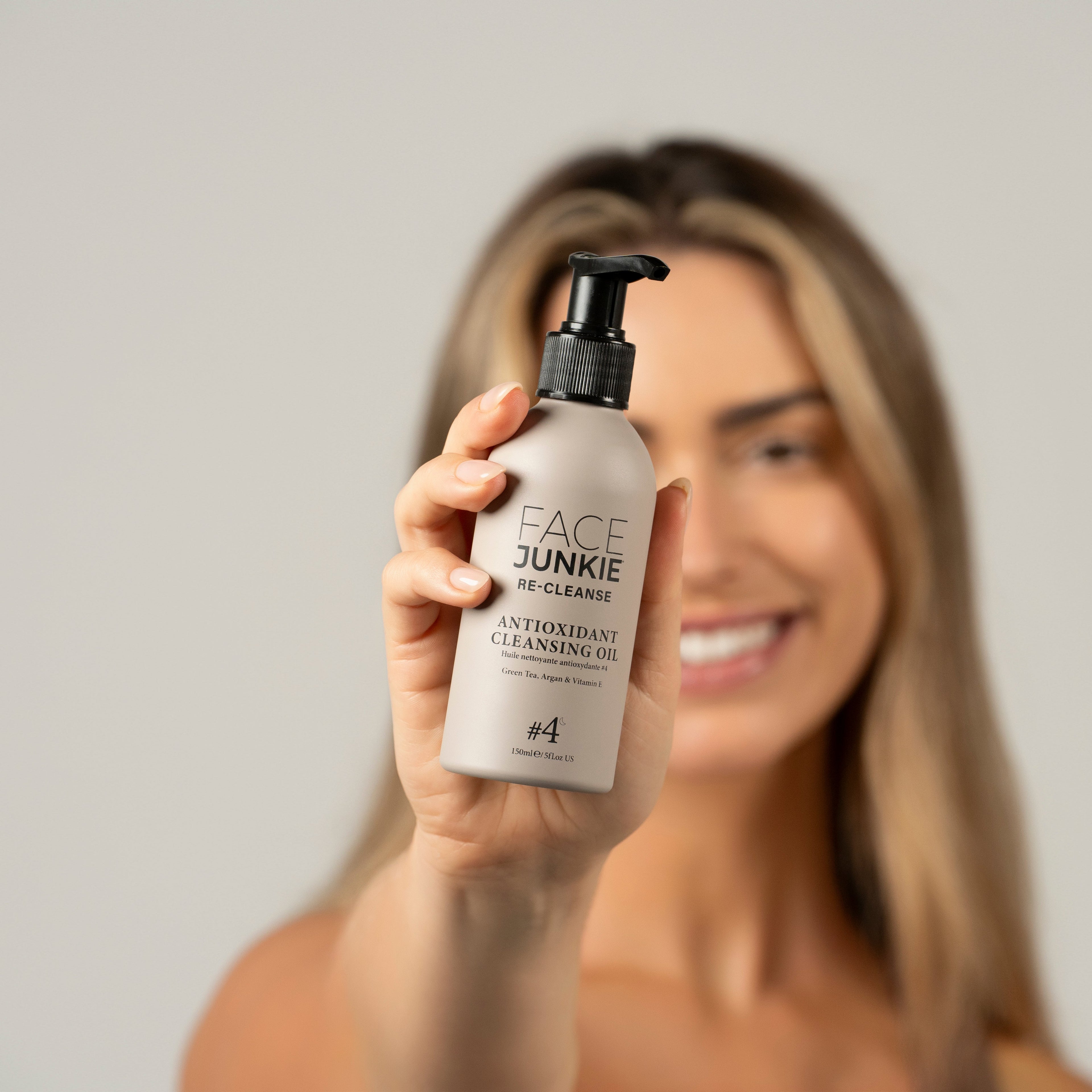 A woman with blonde hair holds a bottle of Face Junkie&