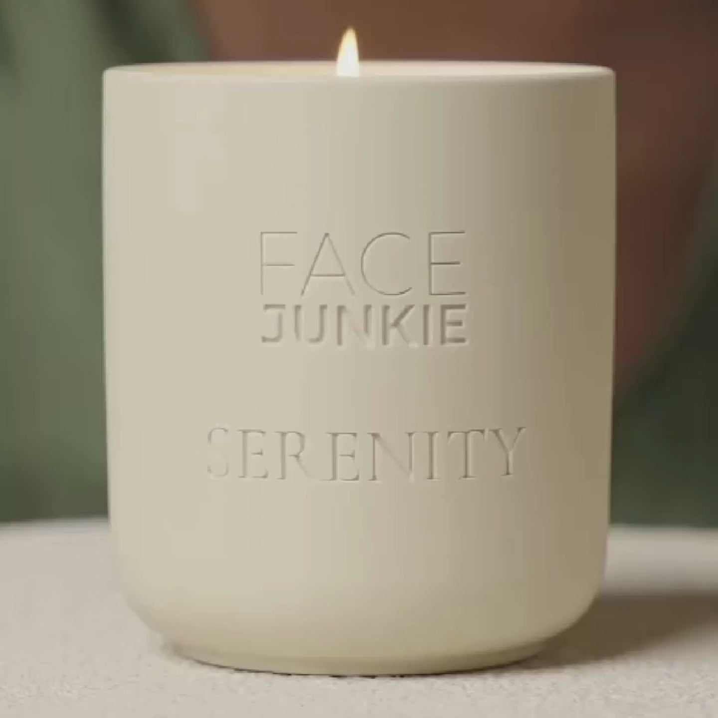 Face Junkie Serenity candle with a minimalist matte design and an elegant embossed logo, softly glowing with a flickering flame. This luxury wellness candle promotes relaxation, mindfulness, and a calming ambiance, aligning with Face Junkie’s holistic approach to self-care and well-being. Perfect for enhancing spa rituals, meditation, and stress relief.