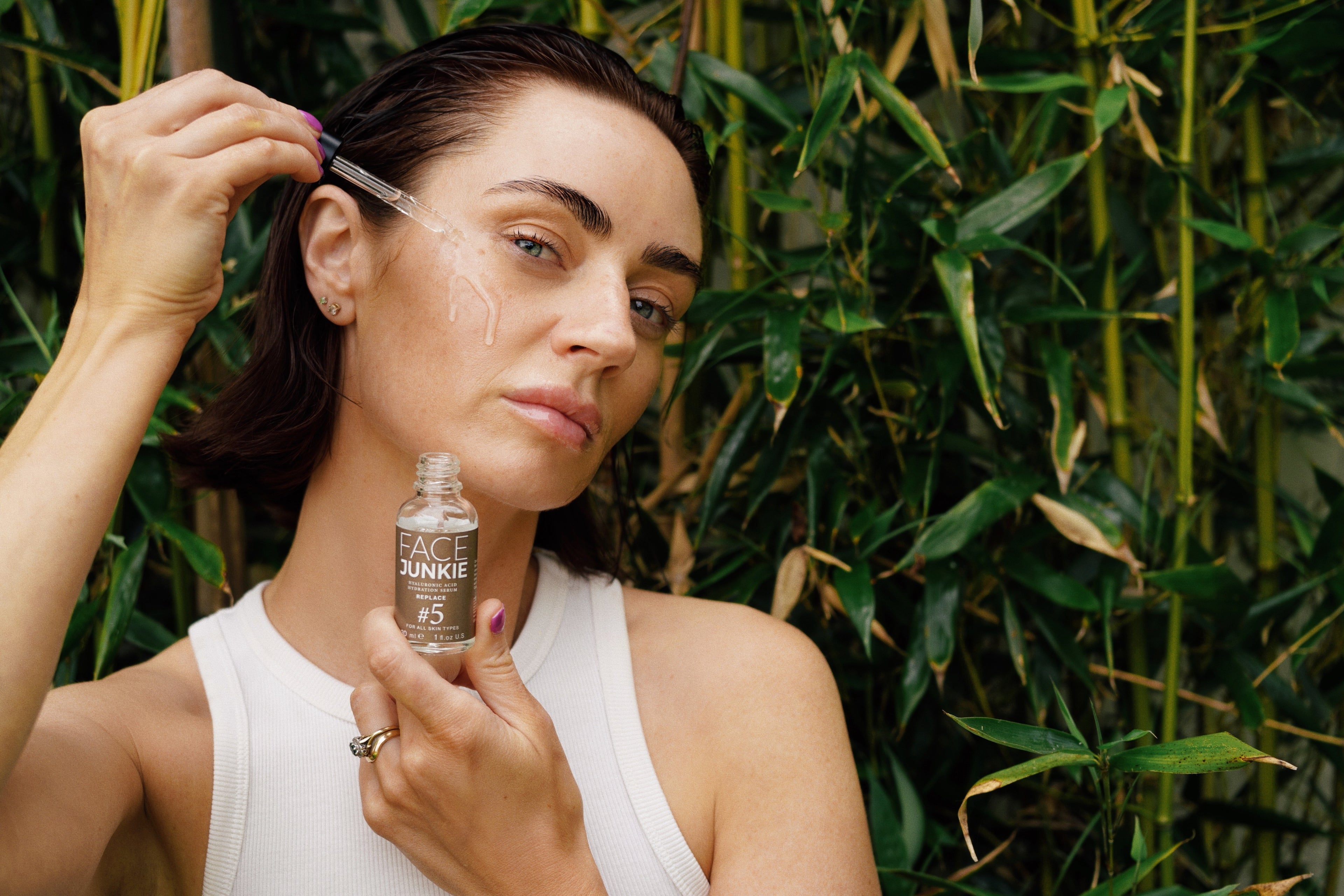 Jen Graham, the radiant face of the Face Junkie Summer Skin Campaign, strikes a pose while showcasing the #5 Hyaluronic Acid Hydrating Serum. In a captivating moment, she delicately drops the serum onto her cheek, embodying the essence of skincare indulgence and the promise of summer-ready, hydrated skin.